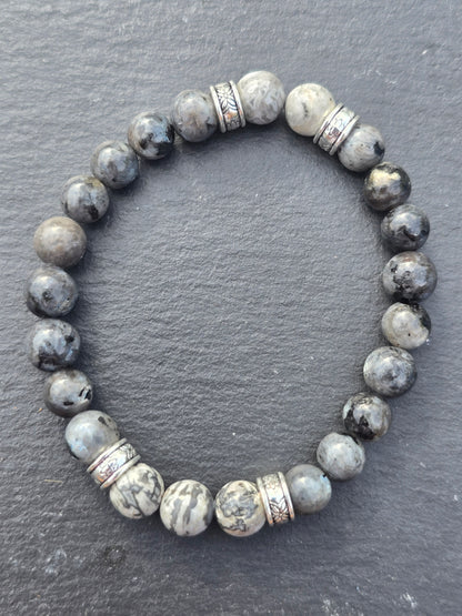 Grey beaded bracelet with silver accents on a dark grey slate background