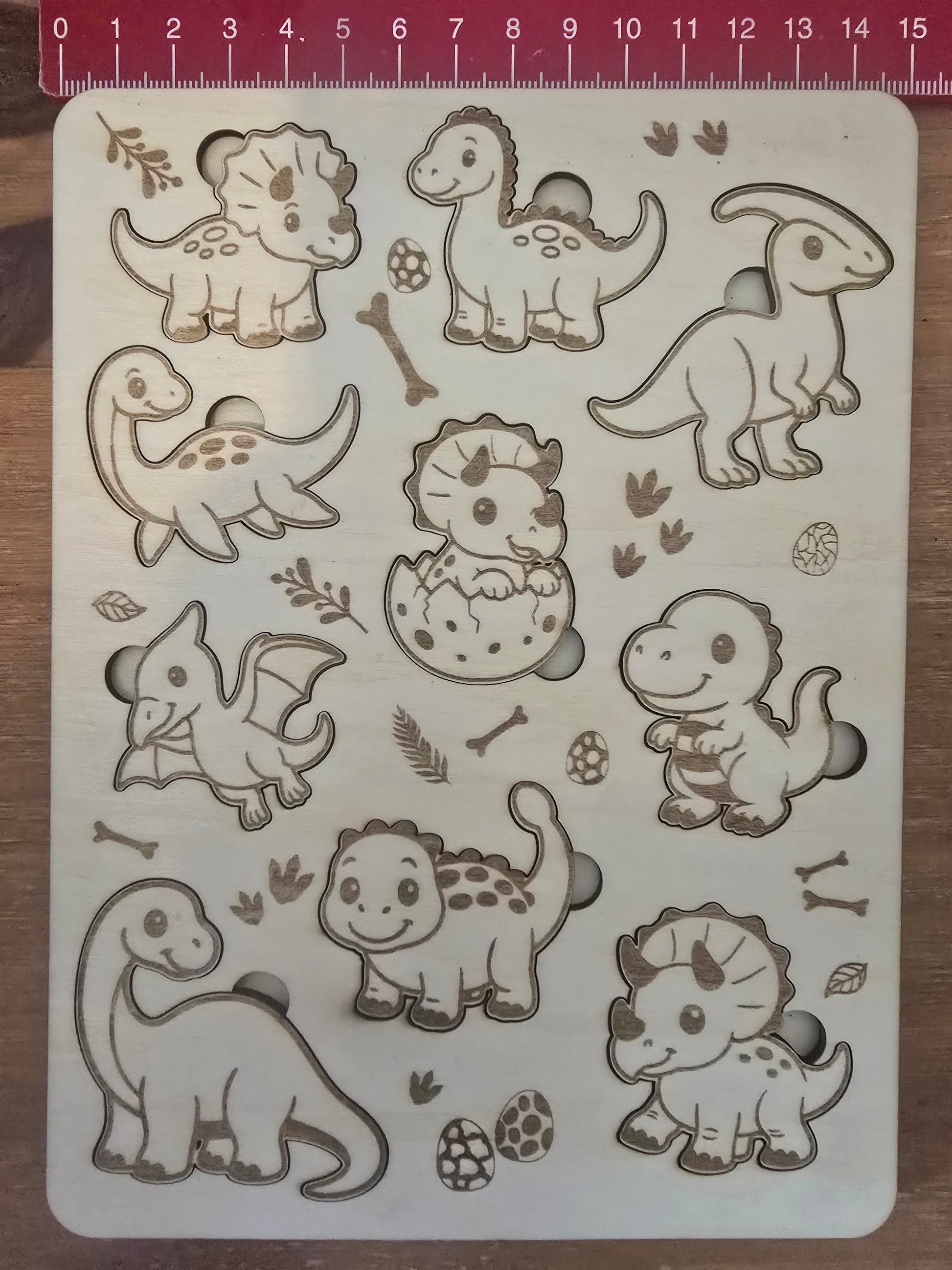 Dinosaur-themed wooden puzzle with measurement scale showing 15cm wide