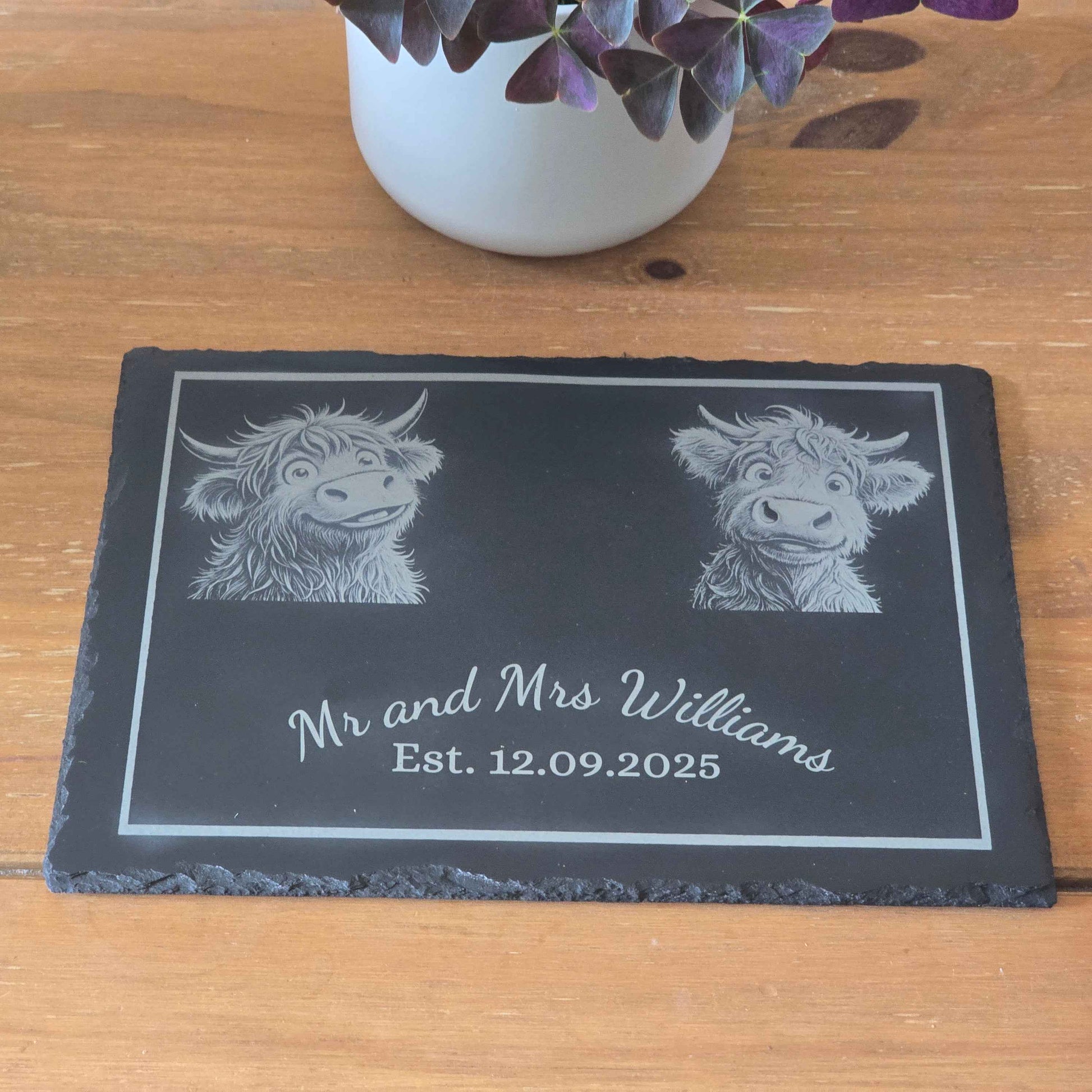 customised slate plaque with engraved highland cows and names on a wooden surface.