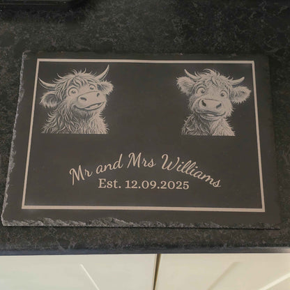 Personalized slate plaque with engraved highland cow illustrations and text on a dark surface.