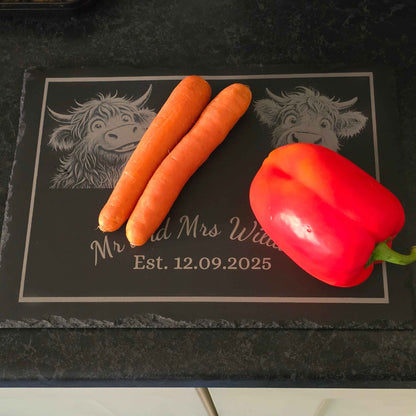two carrots and a red pepper on a decorative slate with engraved cow designs and text.