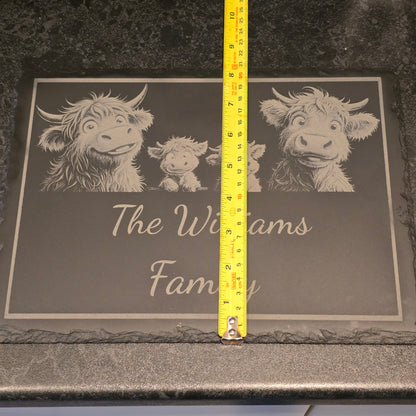 Decorative mat with engraved highland cows and 'The Williams Family' text, measured with a tape measure depicting 21cm width