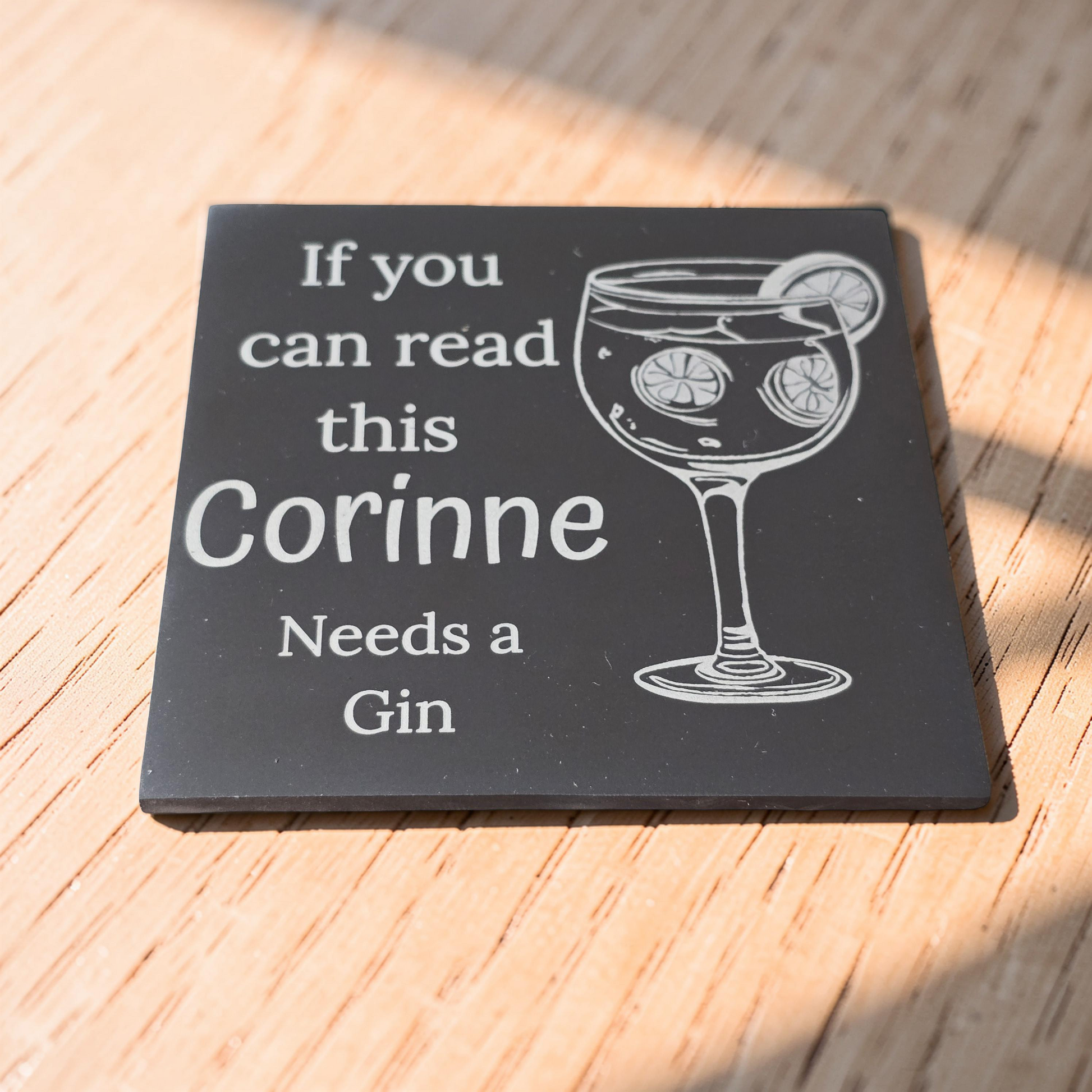 Personalised slate coaster with a glass of gin and text on a wooden surface