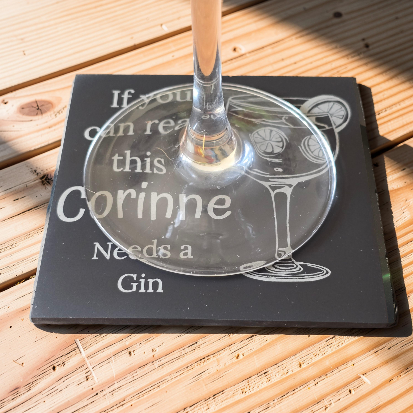 slate coaster with text 'If you can read this Corinne Needs a Gin' on a wooden surface