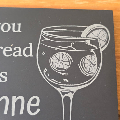 Slate coaster with a glass of gin and lemon slices on a dark background