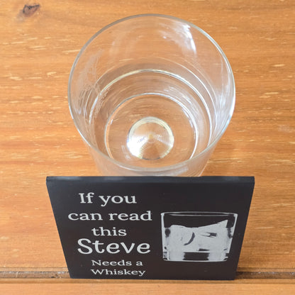 Clear glass and humorous coaster on a wooden surface