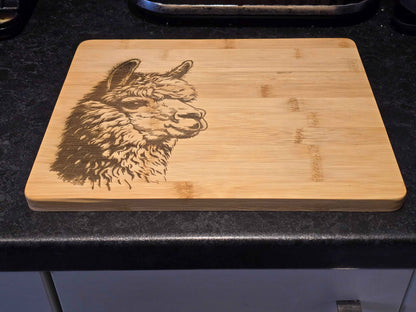 Bamboo Chopping board with engraved alpaca design on a dark surface