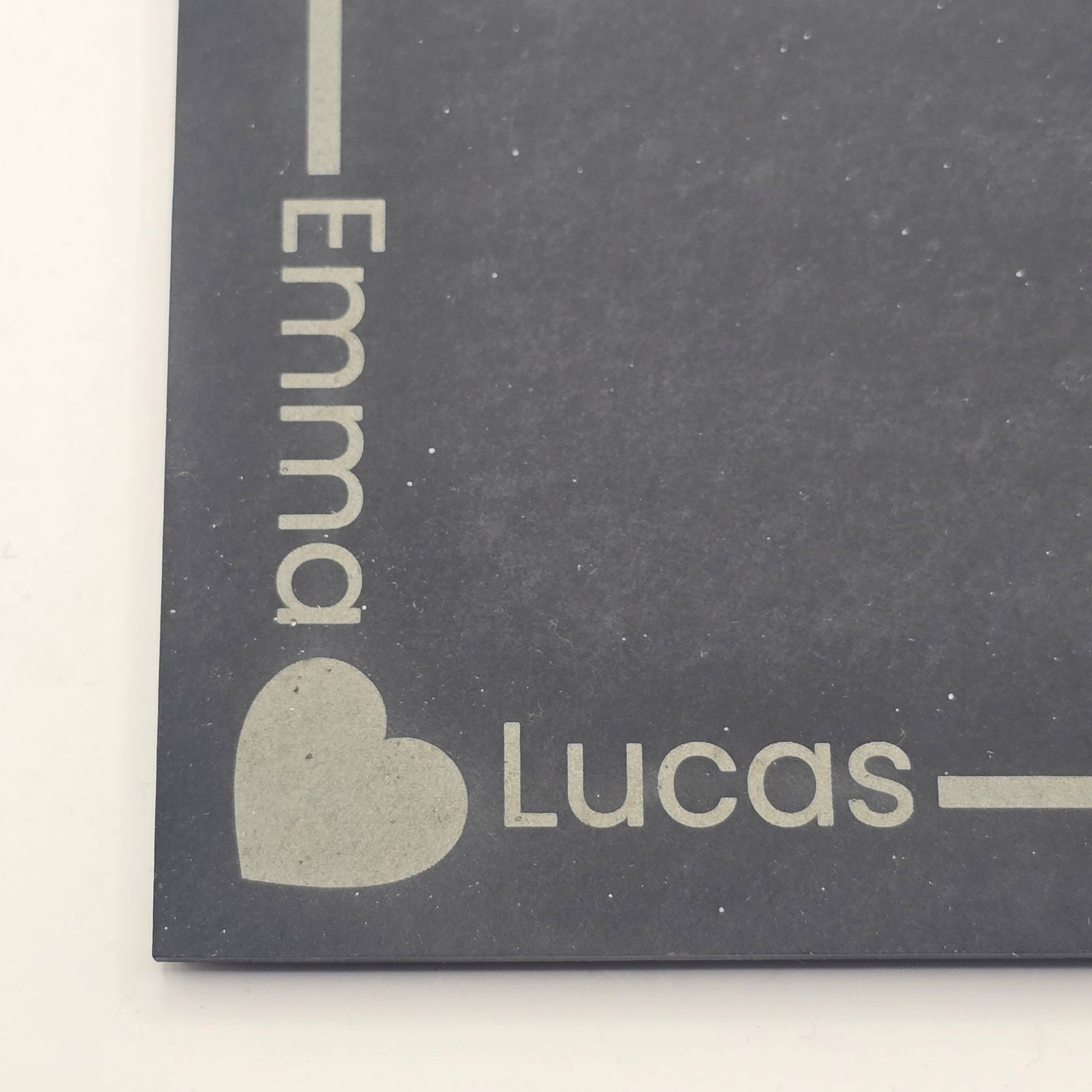 Personalised slate with 'Emma' and 'Lucas' engraved on a dark grey background