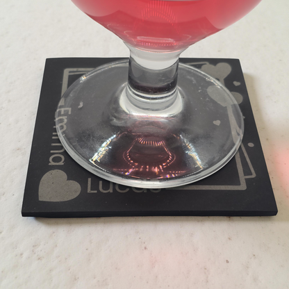 Cocktail glass with red liquid on a black coaster with personalised engraving