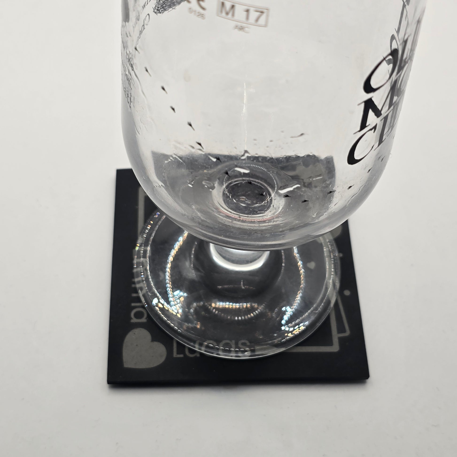 Close-up of a cider glass on a black coaster with heart design