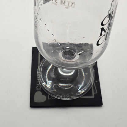 Close-up of a cider glass on a black coaster with heart design