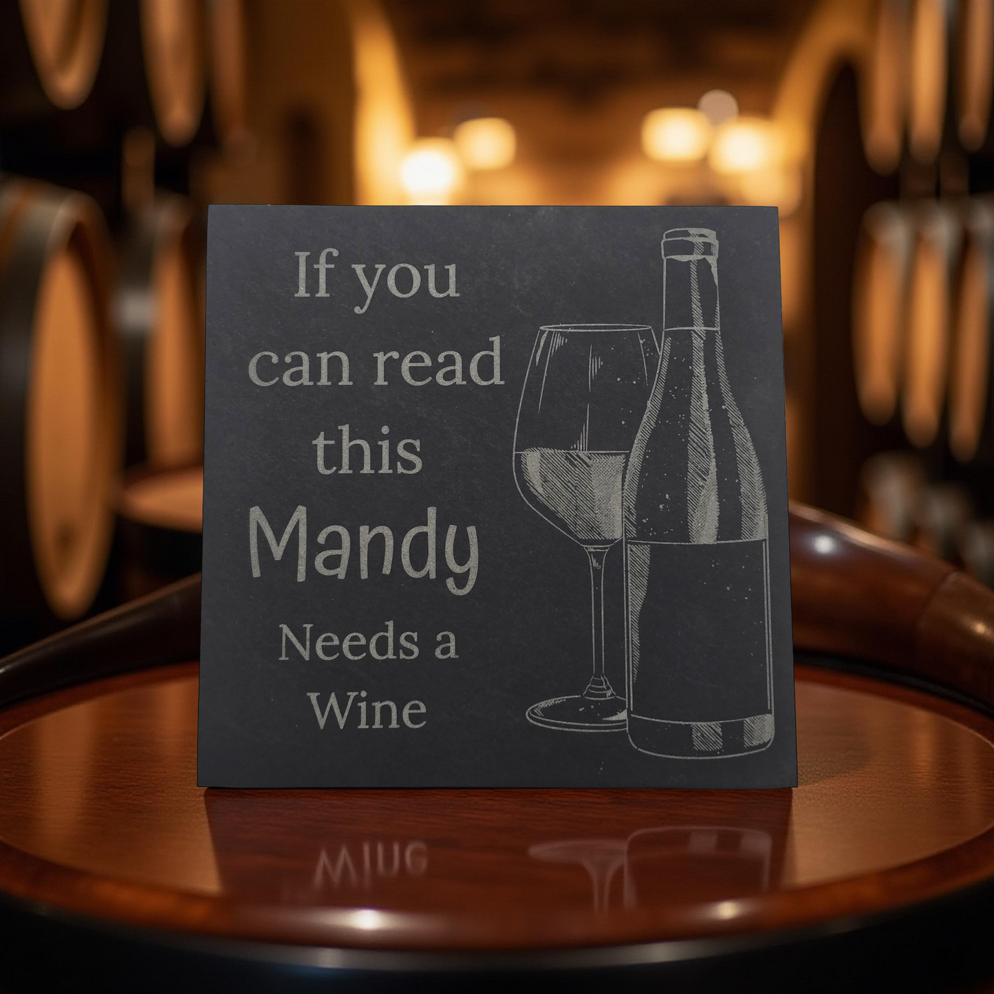 personalised coaster with wine bottle and glass illustration and text 'If you can read this Mandy Needs a Wine' on a wooden surface.