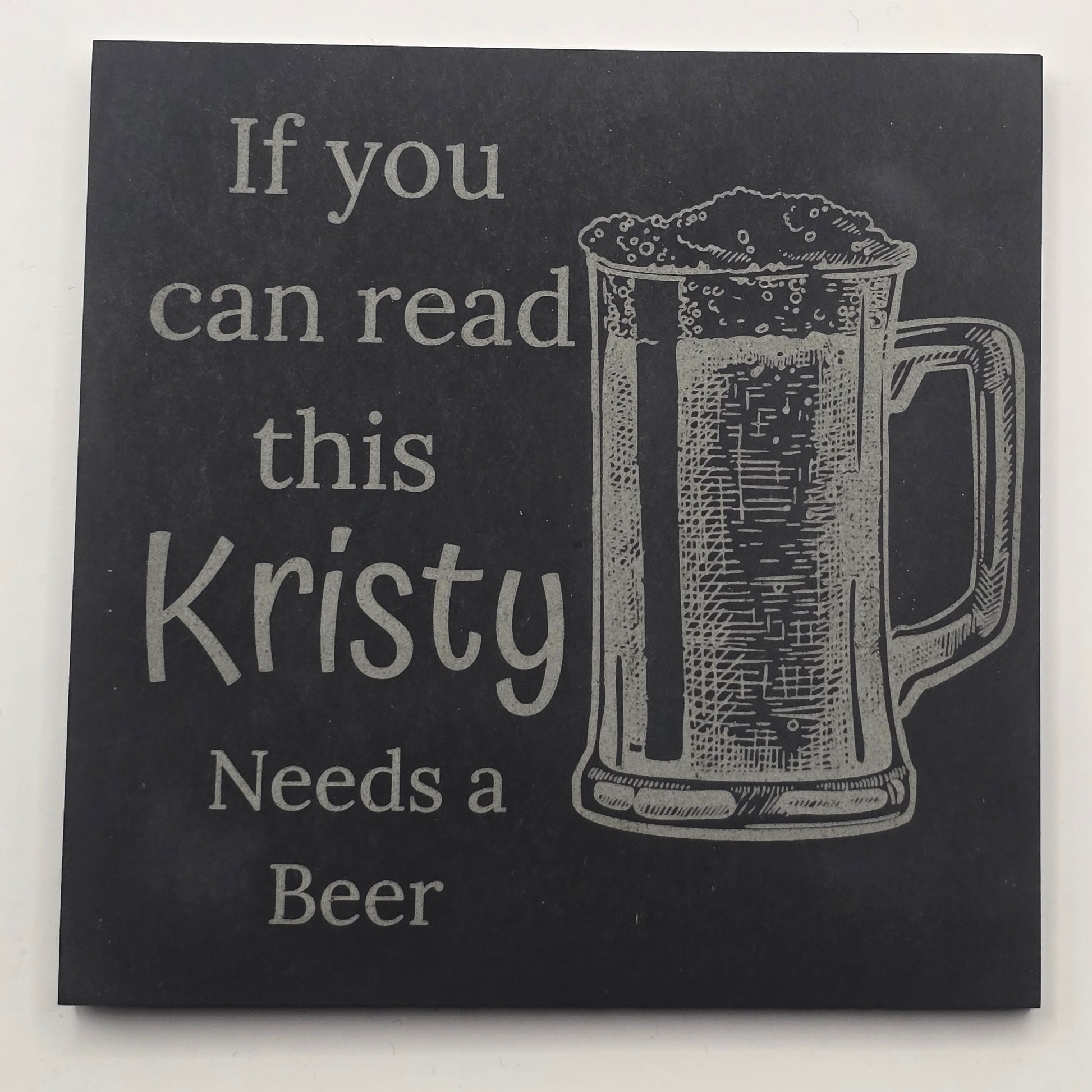 personalised Black slate coaster white text and a beer glass engraving, featuring the phrase 'If you can read this, Kristy Needs a Beer'.