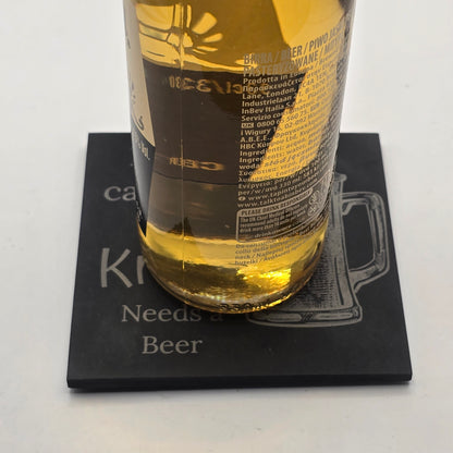 Bottle of beer resting on a black slate coaster with  a 'Beer' quote on a white background