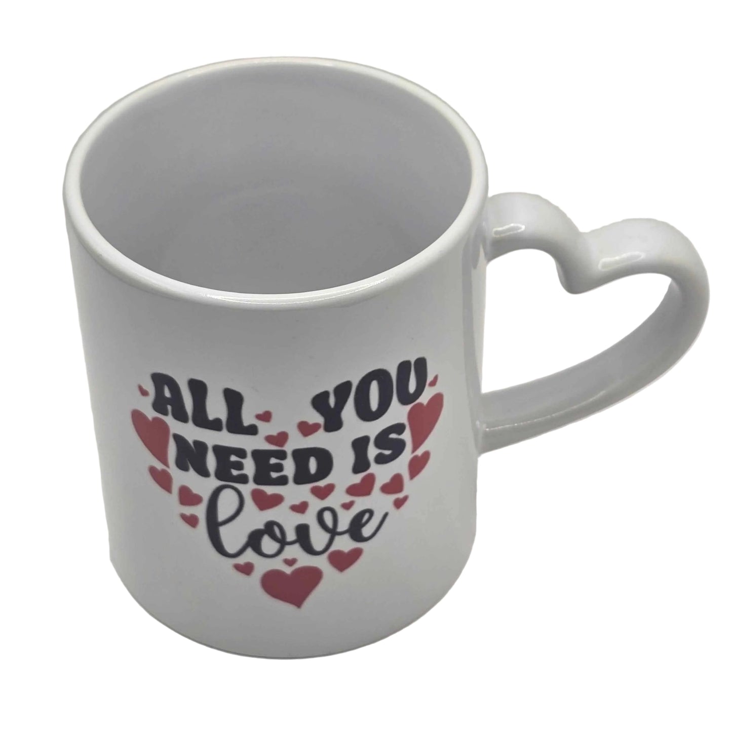 White mug with heart-shaped handle and 'All You Need Is Love' text on a white background