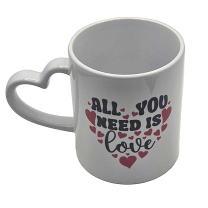 White mug with heart handle and 'All you need is love' text on a white background