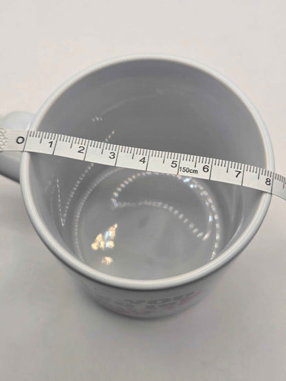 white mug with a ruler showing measurements of 8cm diameter on a light Gray background
