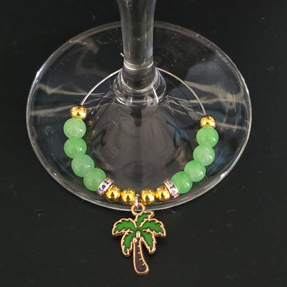 Green beaded cocktail glass charm with gold accents and a palm tree charm on a glass.