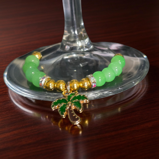 Green and gold beaded wine charm with a Palm treen dangle charm round a wine glass stem