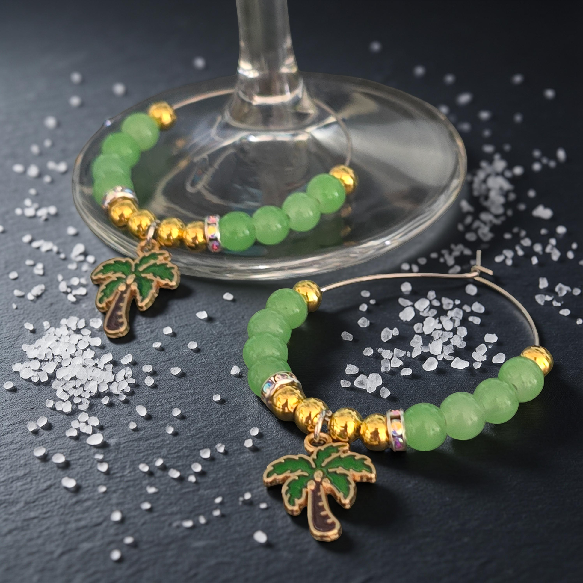 Green beaded Wine Glass charms with palm tree accent on a dark surface
