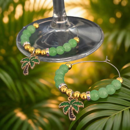Green beaded wine glass charm with palm tree design on a glass against a blurred green leafy background