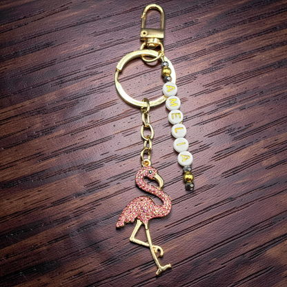 Keychain with flamingo charm and letter beads on a wooden surface