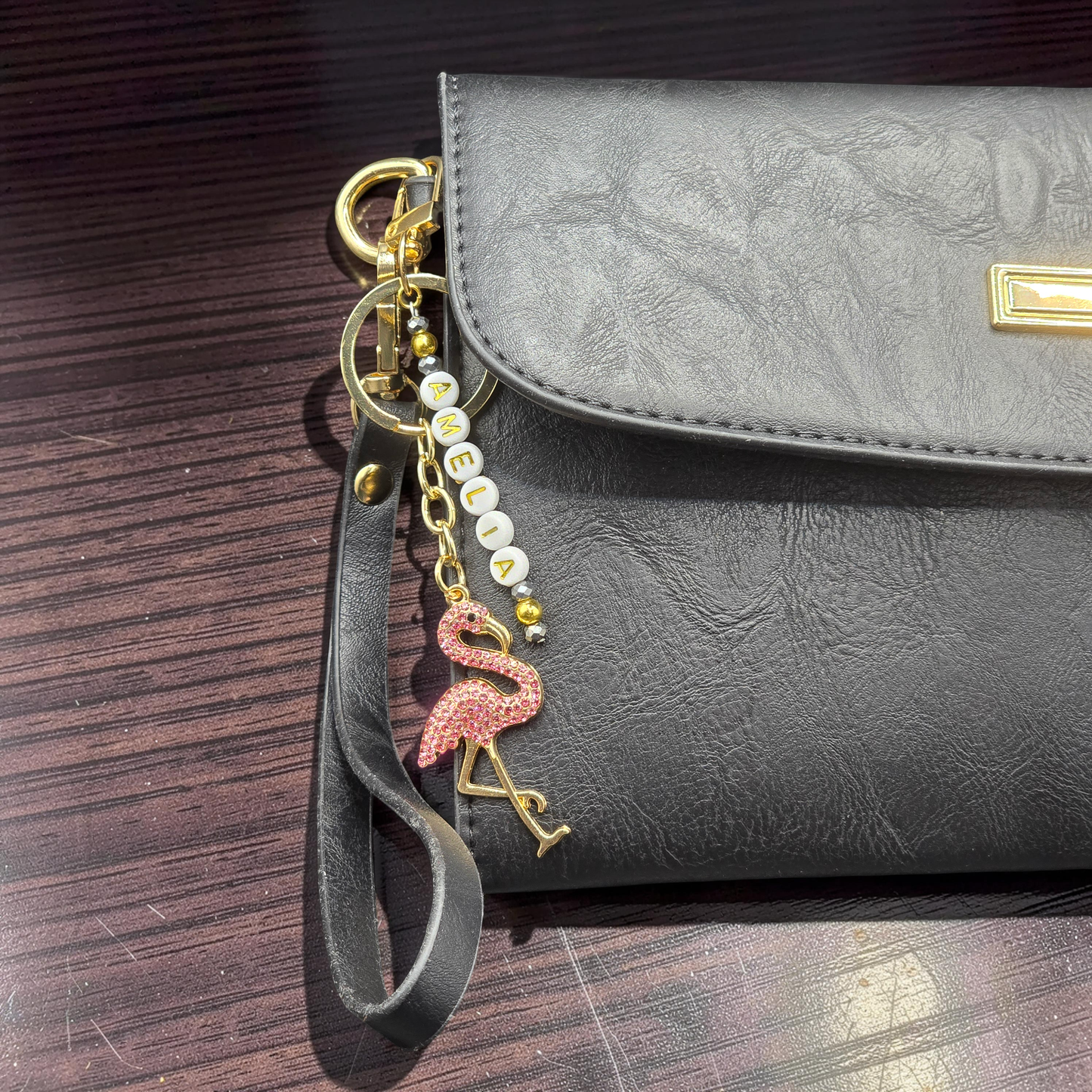 Black handbag with a flamingo bag charm and custom lettered beads