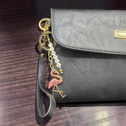 Black handbag with a flamingo bag charm and custom lettered beads