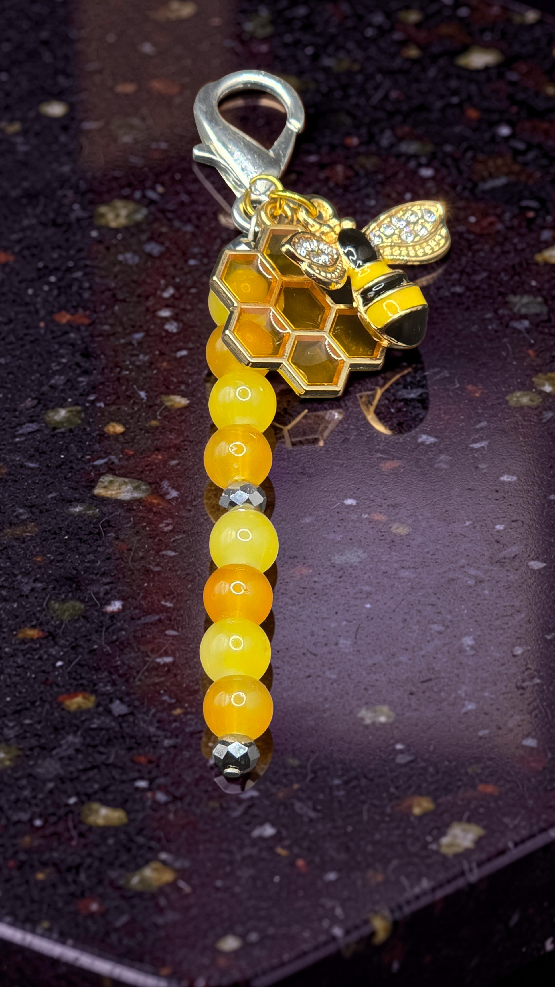 zip charm with honeycomb and bee design on a dark surface