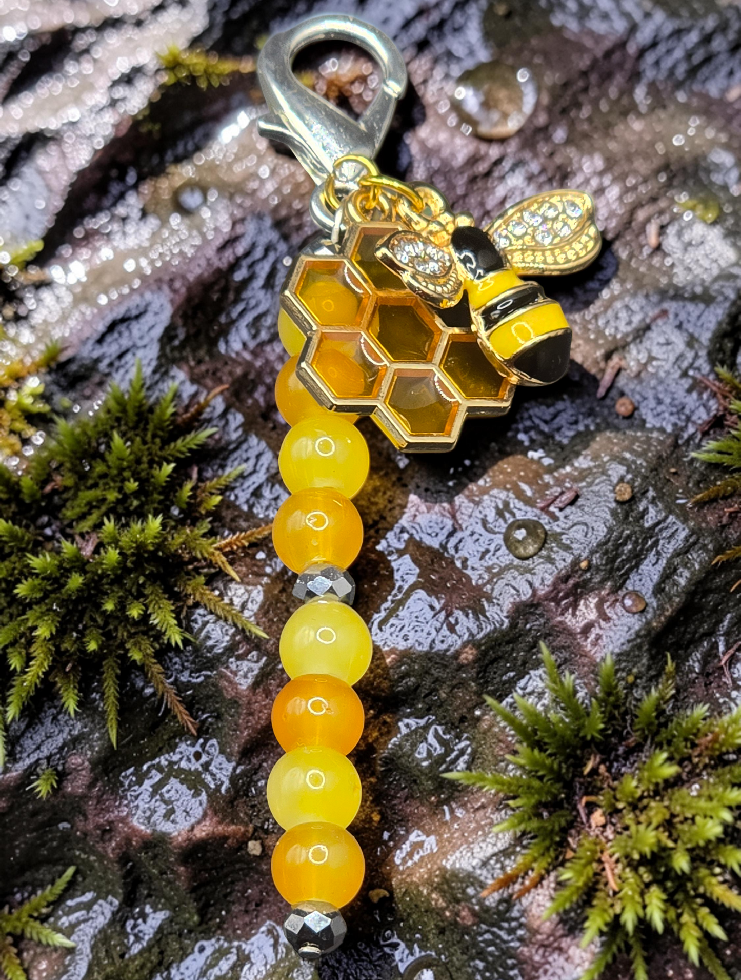 Zipper charm with honeycomb and bee design on a textured surface