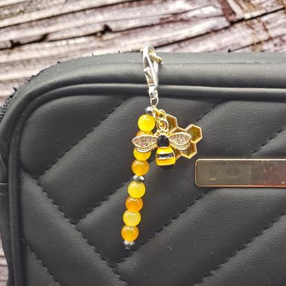 Keychain with bee and honeycomb design on a black textured surface