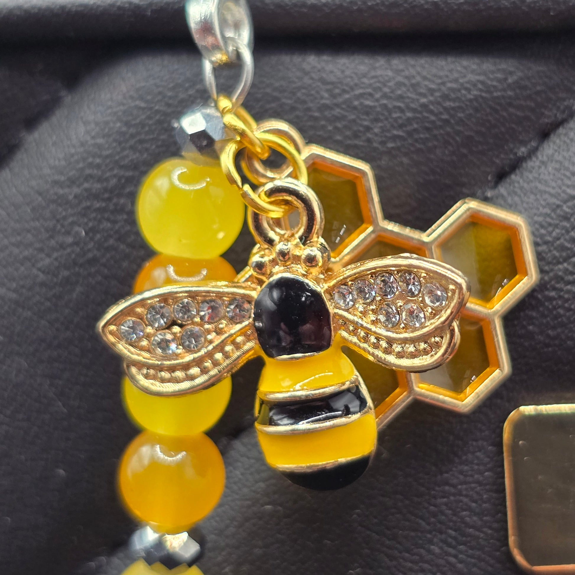 close up of a gold bee charm with rhinestone encrusted wings as part oh a handmade zipper charm