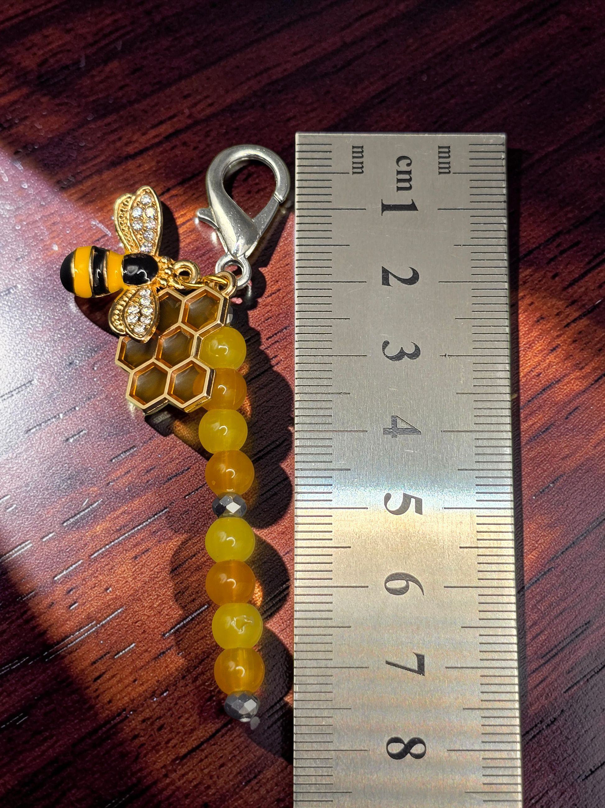 Bee and honeycomb bag charm with beads next to a ruler showing 7.5cm length
