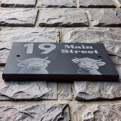 House number sign with Highland cow engravings on a stone wall