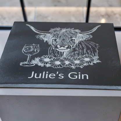 close up low angle shot of a personalised slate coaster with highland cow engraving and custom name text.