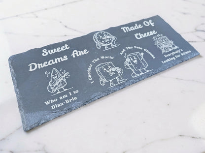 Rectangular slate board engraved with cartoon cheese musicians and cheese-themed Sweet Dreams lyrics.