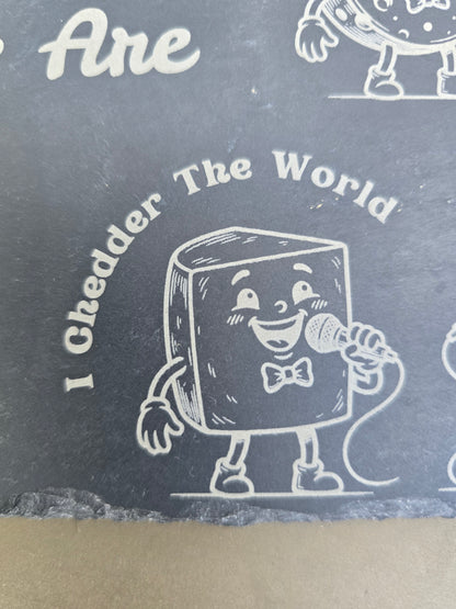 Engraved slate board detail of a cartoon cheese singing into a microphone under the words I Chedder The World.