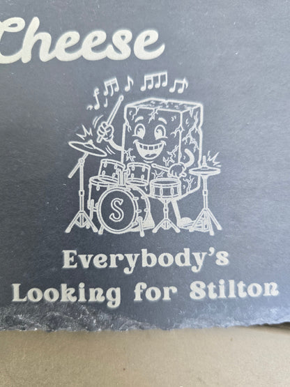 Engraved slate detail of a cartoon cheese playing drums above the phrase Everybody's Looking for Stilton.