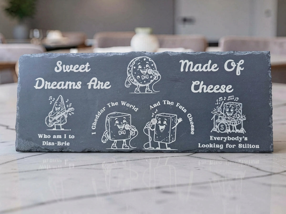 Dark slate cheese board engraved with cartoon cheese characters and the pun Sweet Dreams Are Made of Cheese.