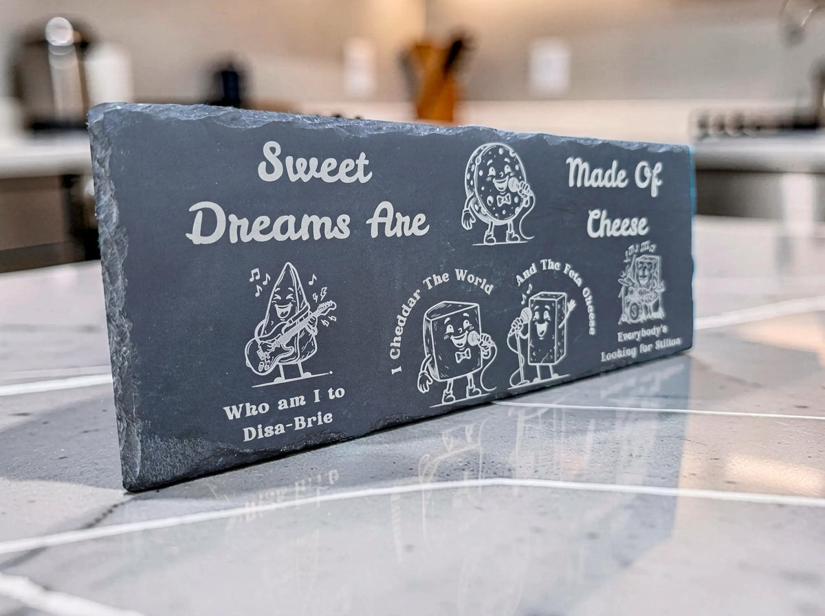 Rectangular dark slate board engraved with cartoon cheese characters and Sweet Dreams Are Made of Cheese lyrics.