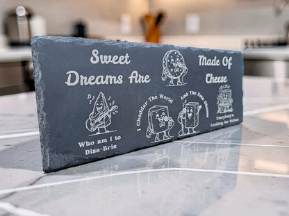 Rectangular dark slate board engraved with cartoon cheese characters and Sweet Dreams Are Made of Cheese lyrics.