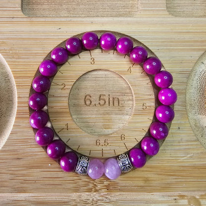 Women's Beaded bracelet with purple and pink beads on a wooden surface with measurement markings showing the size as 6.5inches.