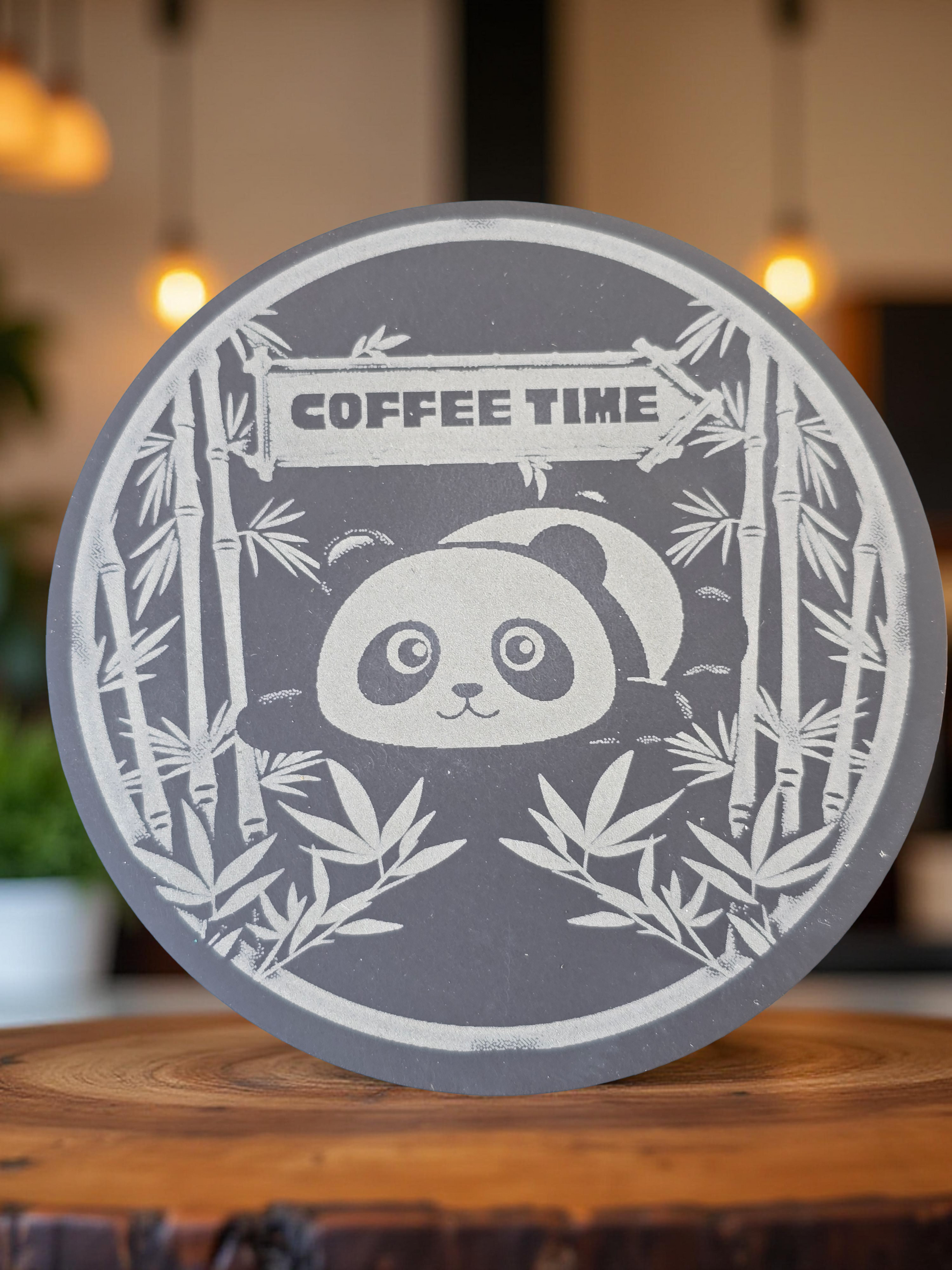 Round slate coaster with panda design and 'Coffee Time' text on a wooden surface.