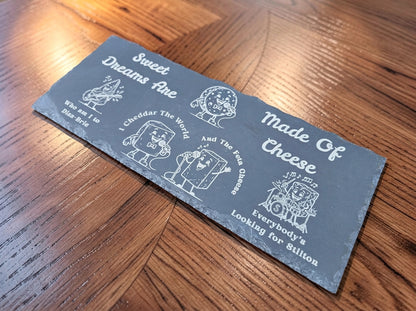 Dark slate board engraved with cartoon cheese musicians and Sweet Dreams Are Made of Cheese song parody lyrics.