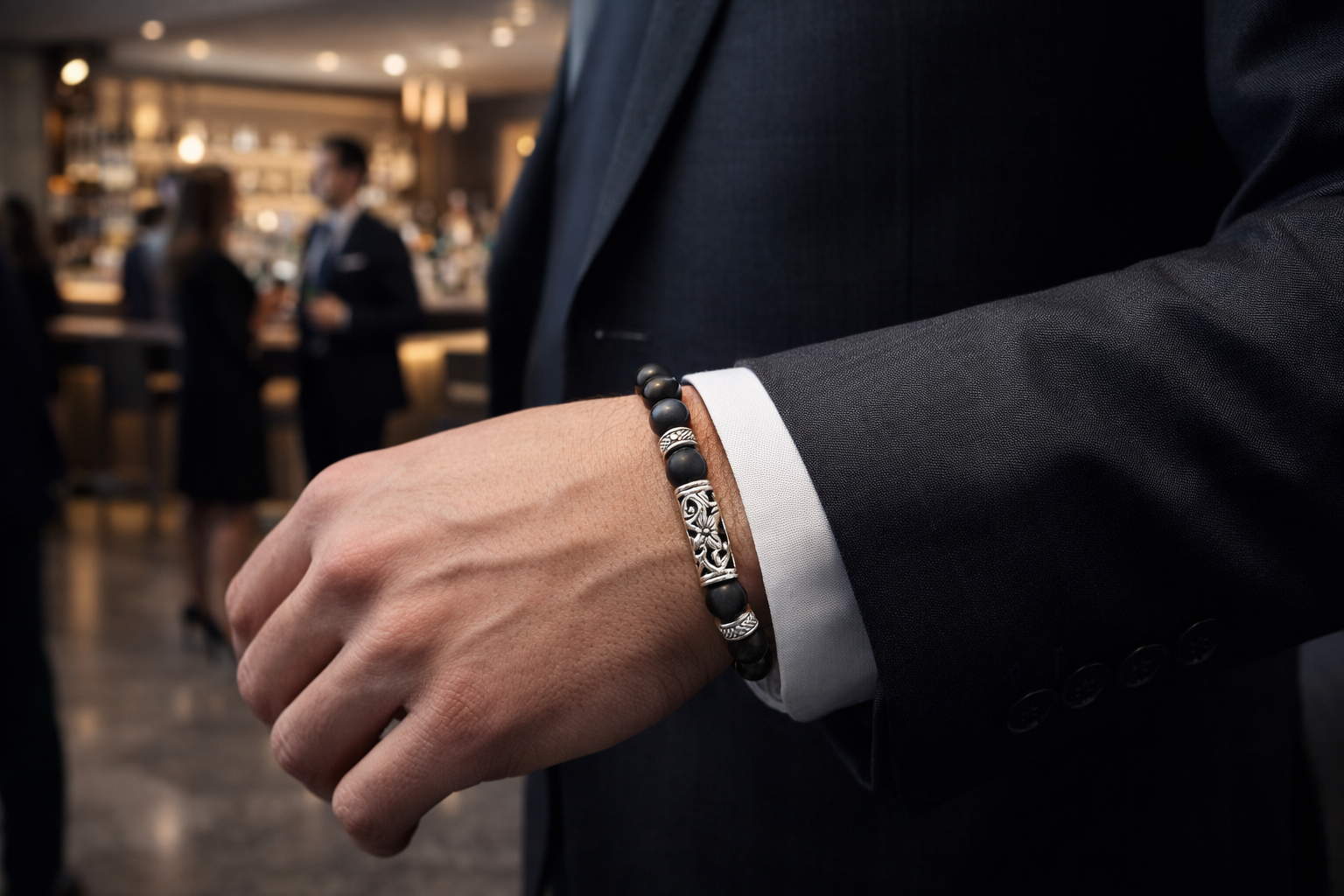 man wearing a matt black beaded bracelet walking through a bar